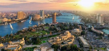 Káhira - Pohled na jižní část ostrova Gezira, kde stojí mj. káhirská Opera (velký žlutý komplex vpravo dole), a centrum Káhiry (vlevo vzadu). Druhý břeh Nilu (vpravo) patří již Gíze