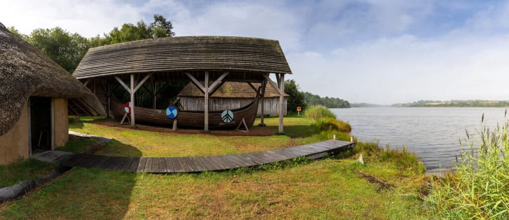 Typický vikingský dlouhý dům a člun ve skanzenu Irish National Heritage Park na břehu řeky Slaney ve Wexfordu