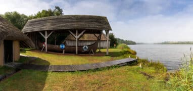 Typický vikingský dlouhý dům a člun ve skanzenu Irish National Heritage Park na břehu řeky Slaney ve Wexfordu