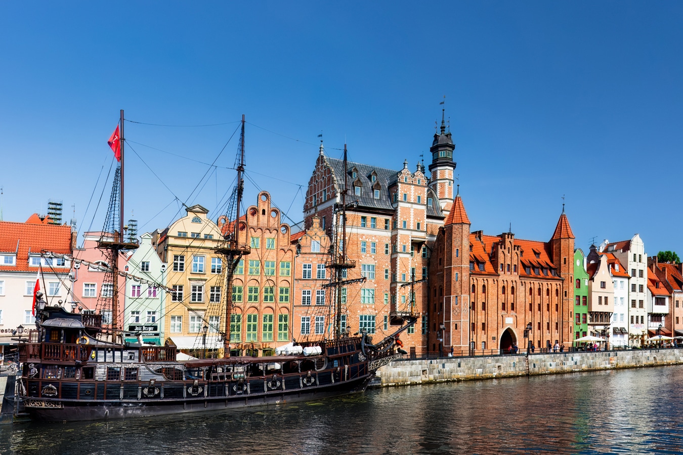 Nábřeží Motławy v Gdaňsku s Mariánskou branou a vlevo od ní nápadně vysokým Domem přírodovědců