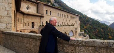 Mnich vyhlíží přes zábradlí v klášteře sv. Benedikta,někdy nazývaném podle jeskyně sv. Benedikta rovněž Sacro Speco